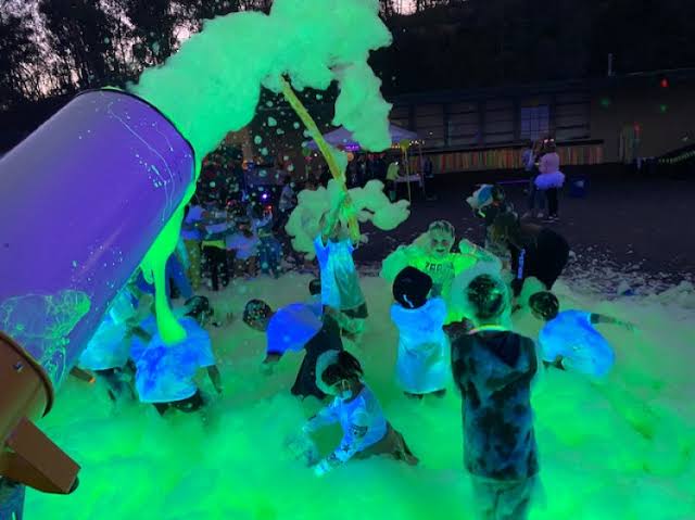 Kids playing under glowing green foam at a Laredo foam party